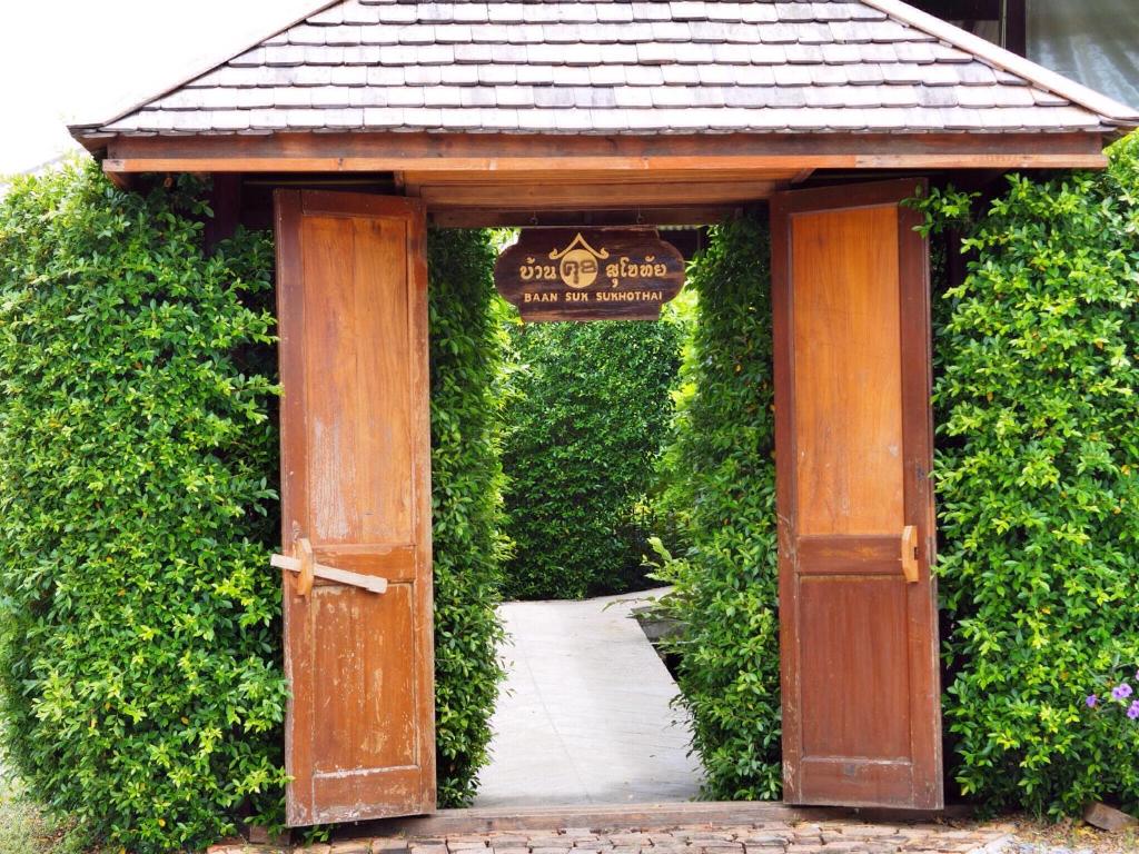 an entrance to a garden with a wooden door at BaanSuk Sukhothai Resort in Sukhothai