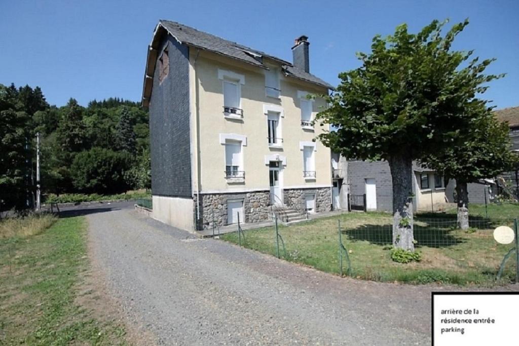 une ancienne maison en pierre avec un arbre sur une route en gravier dans l'établissement Doux Ombrages, à La Bourboule