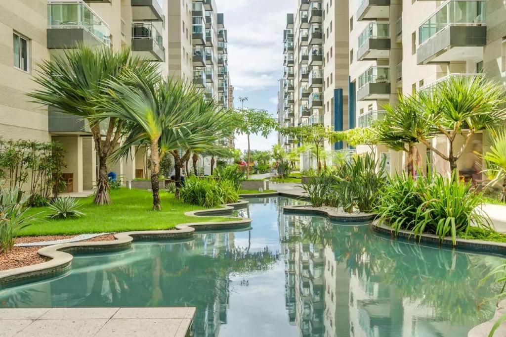 a swimming pool with palm trees and buildings at Apartamento Beira Mar Maceió in Maceió