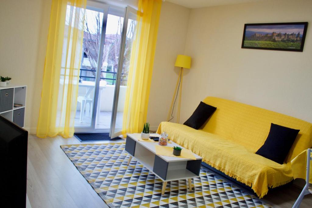 uma sala de estar com um sofá amarelo e uma mesa em Appart Chrystal em Carcassonne