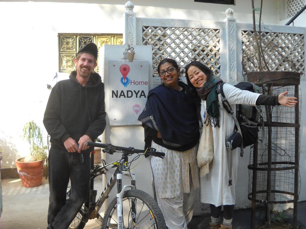 grupa trzech osób stojących obok roweru w obiekcie Nadya Homestay For Female & family w mieście Dżajpur