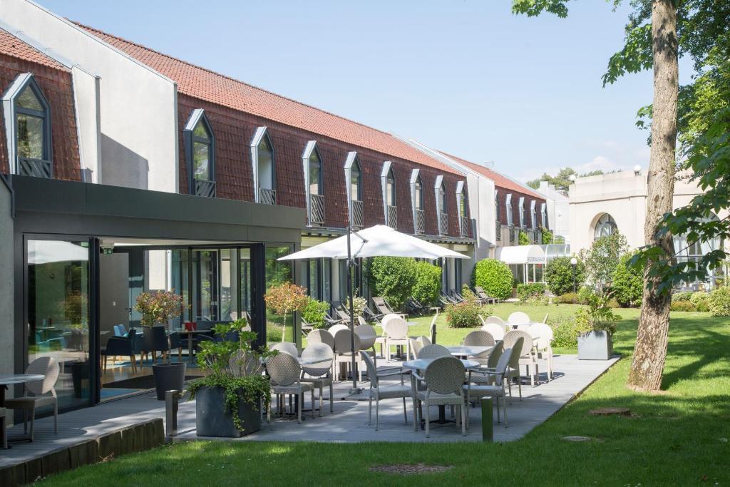 um pátio com mesas e cadeiras brancas e um edifício em Holiday Inn Resort le Touquet, an IHG Hotel em Le Touquet-Paris-Plage