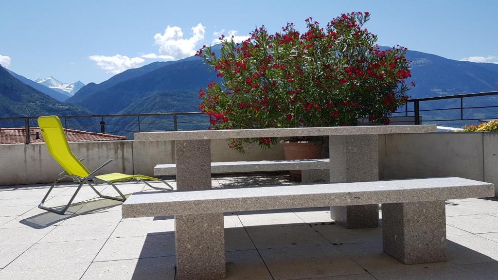 a bench and a chair on a balcony with mountains at Studio dans une villa à Veyras in Veyras