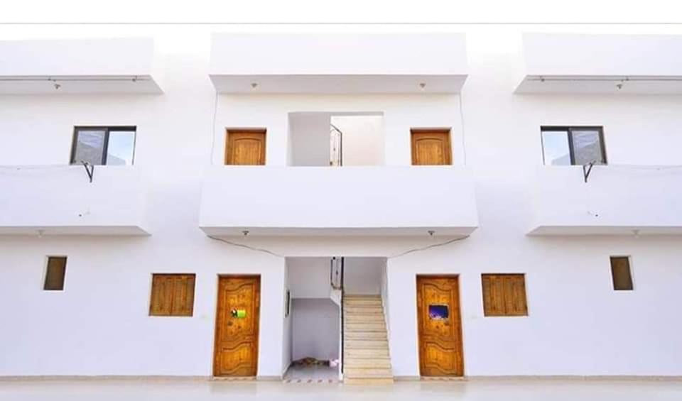 a white building with wooden doors and a staircase at A5ena House in Dahab