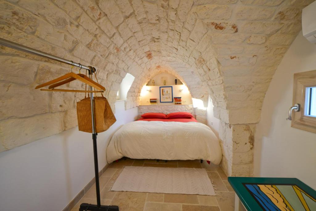 Ostuni Guest House في أوستوني: غرفة نوم بسرير في جدار حجري
