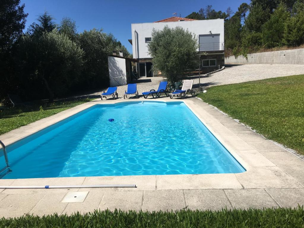 a pool with chairs and a house in the background at Quinta da Marialva in Mangualde