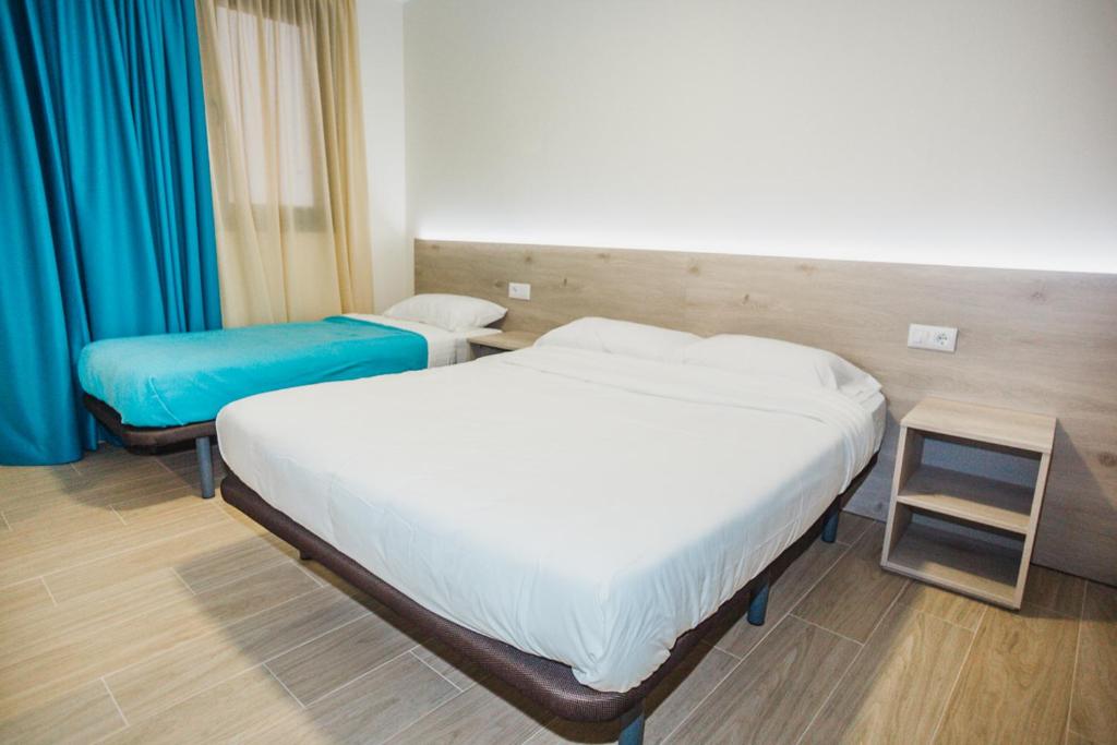 a bedroom with two beds and a table and blue curtains at Solesperit in Lloret de Mar
