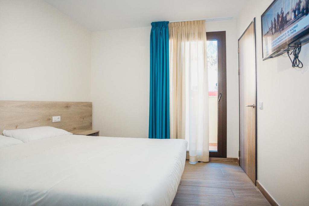 a bedroom with a white bed and a blue curtain at Solesperit in Lloret de Mar