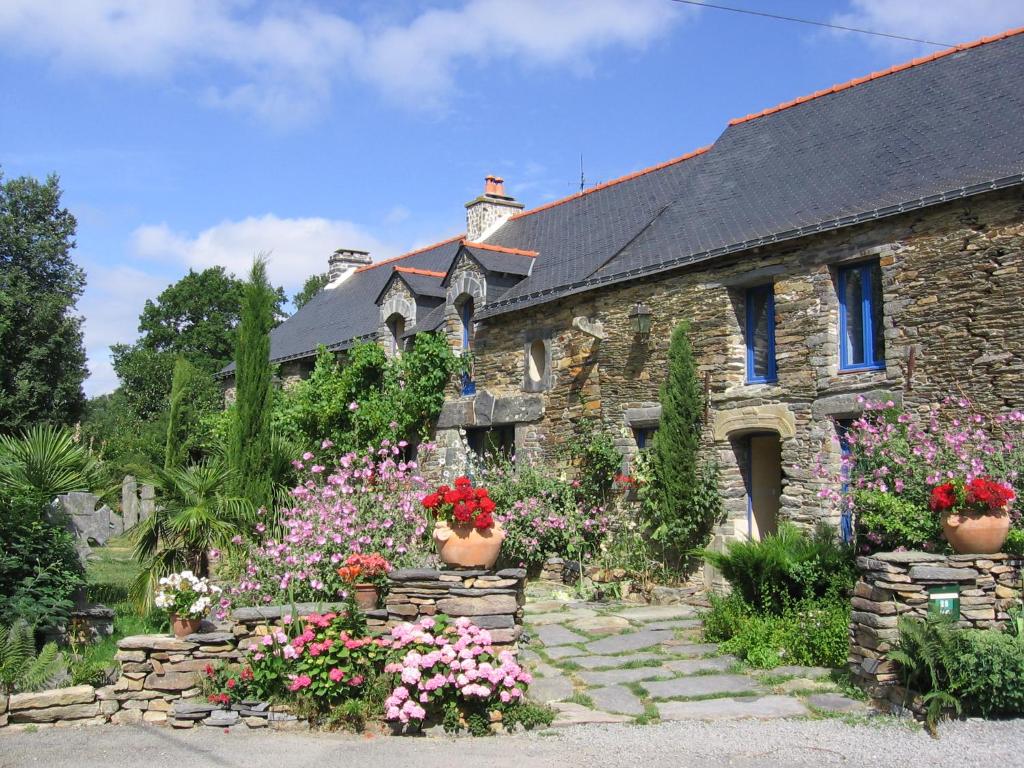 uma casa de pedra com flores em frente em Le clos du Tay em La Gacilly