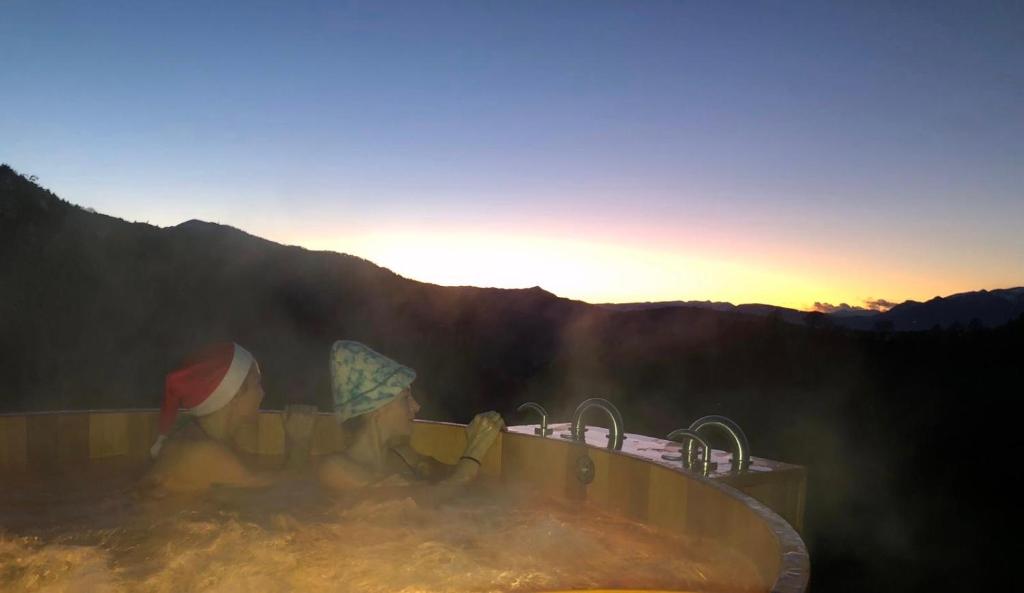 a hot tub with the sun setting in the mountains at Rifugio Pranolz in Trichiana