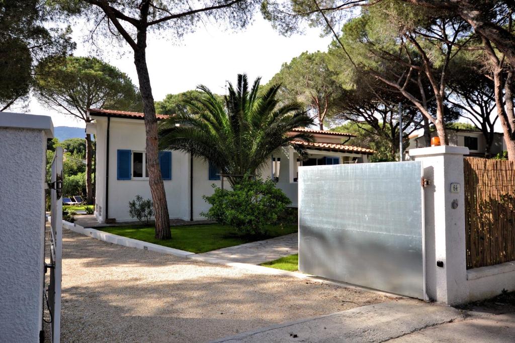 einen weißen Zaun vor einem Haus mit Bäumen in der Unterkunft Villa Montecristo in Marina di Campo