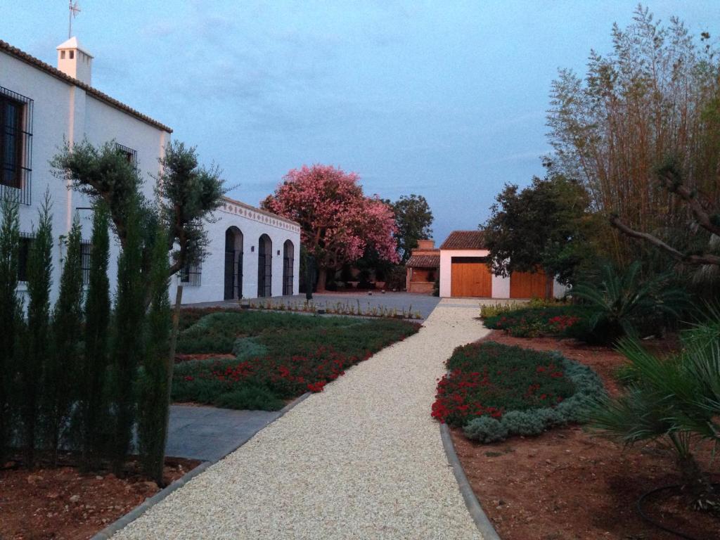 a walkway in front of a white building with flowers at Huerto del Medico in Reig