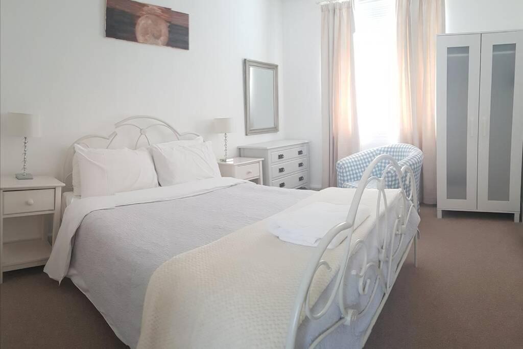 una camera bianca con un letto bianco e una sedia di Quirky Coach House a Plymouth