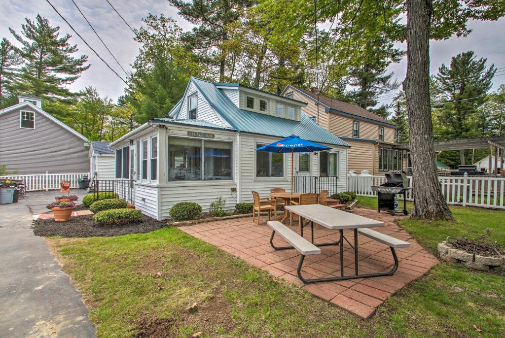 a house with a table and an umbrella in the yard at Sebago Lake Cottage with Patio and Beach Access! in North Sebago