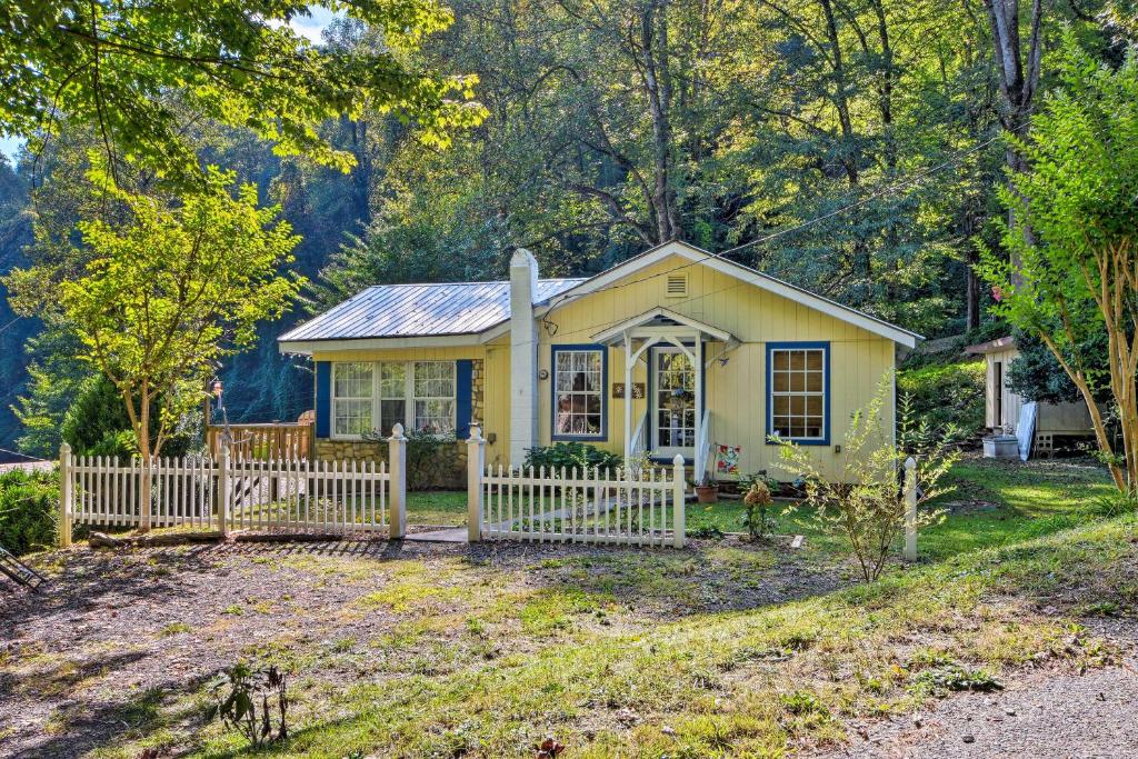 a small yellow house with a white fence at Mountain Cottage with Views Near Tail of the Dragon! in Fontana Village