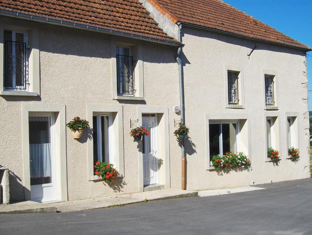 a white building with flower boxes on the windows at La Boulonne in Festigny