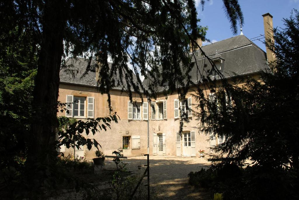 una grande casa in mattoni con un albero di fronte di La Maison des Gardes - Chambres d'hôtes a Cluny