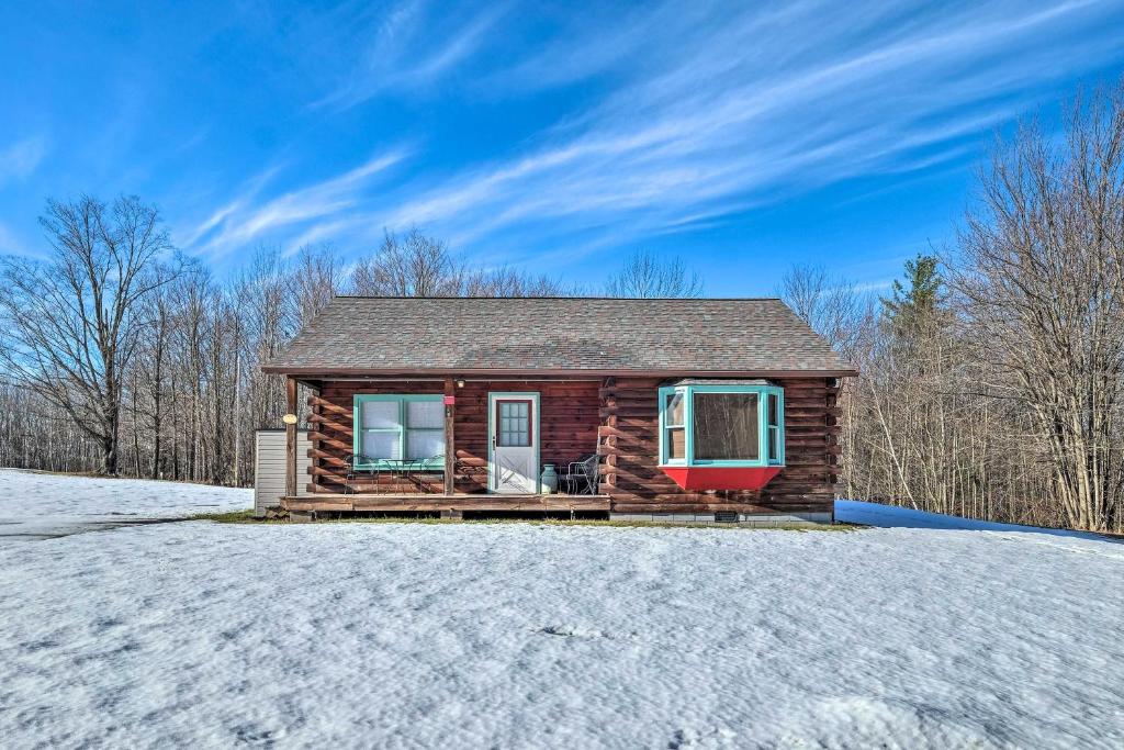 a log cabin with a red door in the snow at High Peak Heaven Cozy Log Cabin on 1 Acre! in Windham