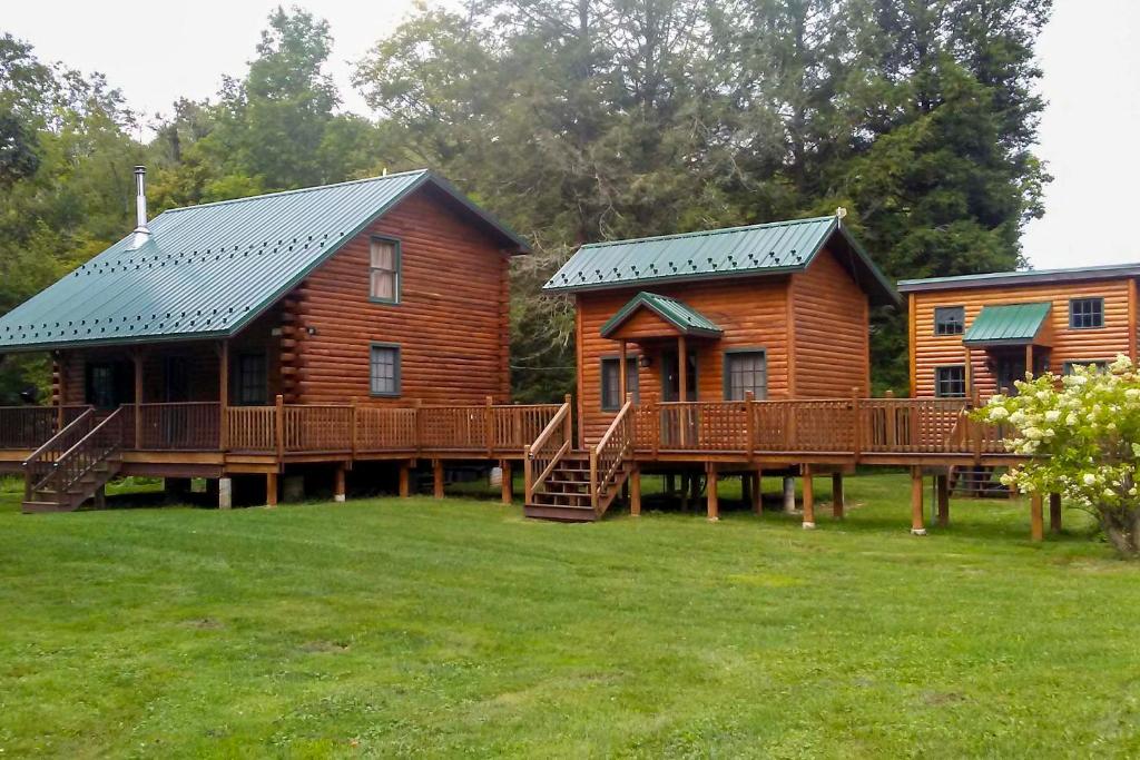 eine Blockhütte mit einer Terrasse und einem Haus in der Unterkunft Scenic Log Cabin with Fire Pit and Stocked Creek! in Titusville