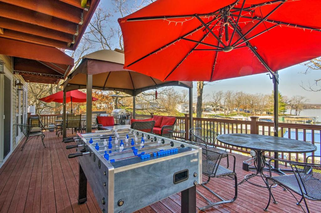 a ping pong table with red umbrellas on a deck at Bayview Lake House with Dock on Lake of the Ozarks in Lake Ozark