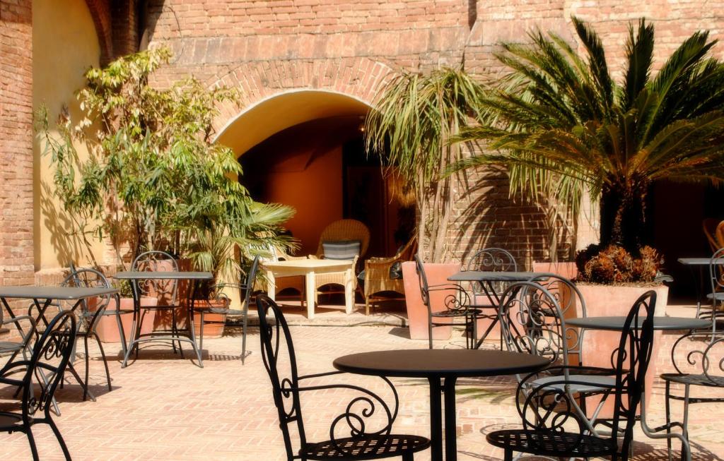 a patio area with tables, chairs and umbrellas at Il Chiostro Del Carmine in Siena