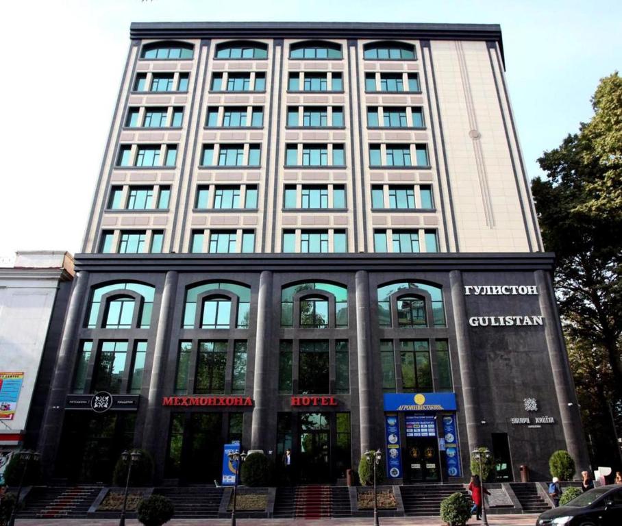 een hoog gebouw met ramen en trappen ervoor bij Gulistan Hotel in Doesjanbe