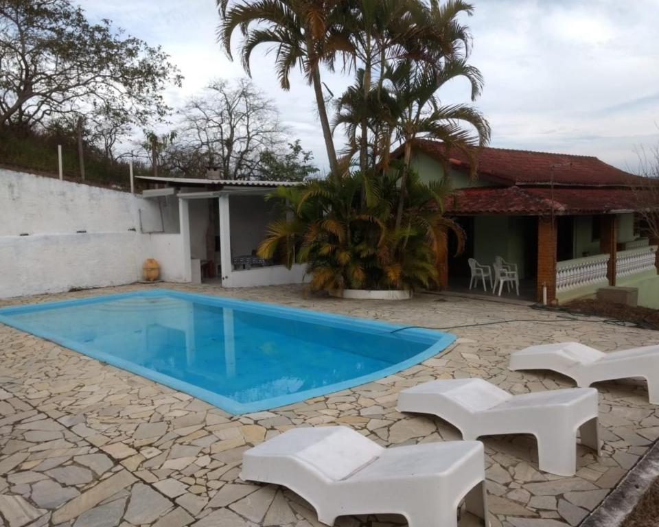 a villa with a swimming pool and a house at Chacara Recanto do Carlão in Biritiba-Mirim