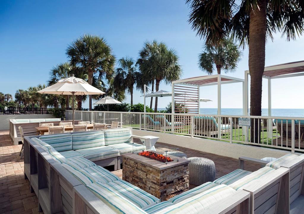 a patio with a couch and tables and the beach at The Strand - A Boutique Resort in Myrtle Beach