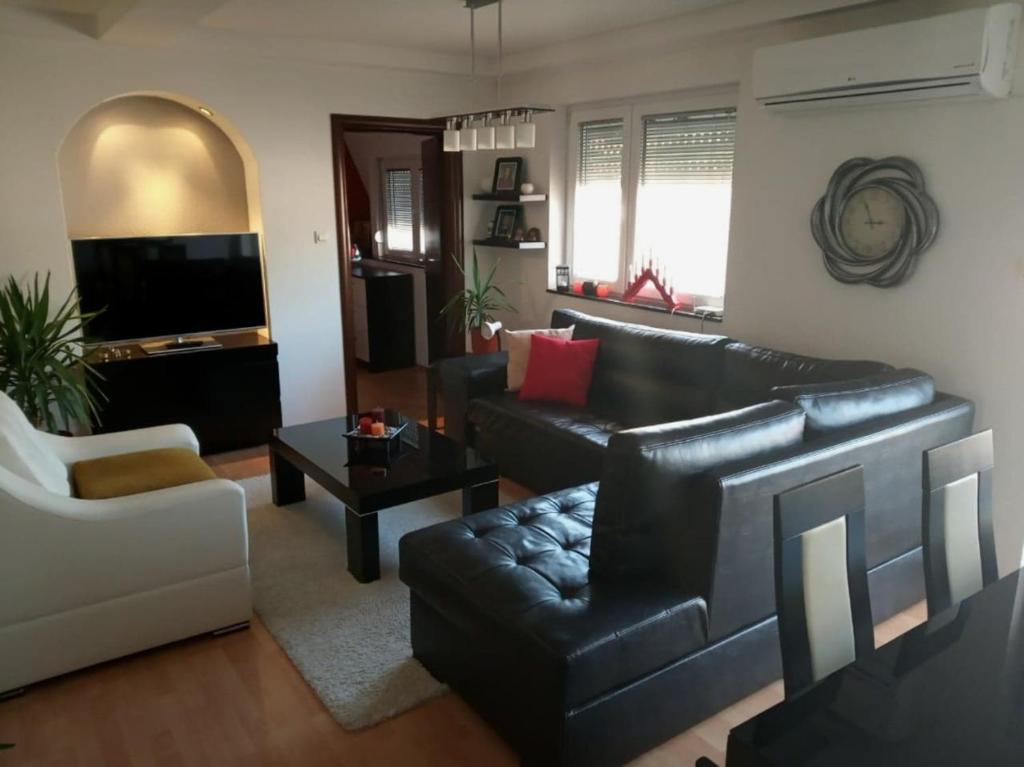 un soggiorno con divano in pelle nera e tavolo di Brand New Apt in City Center a Bitola