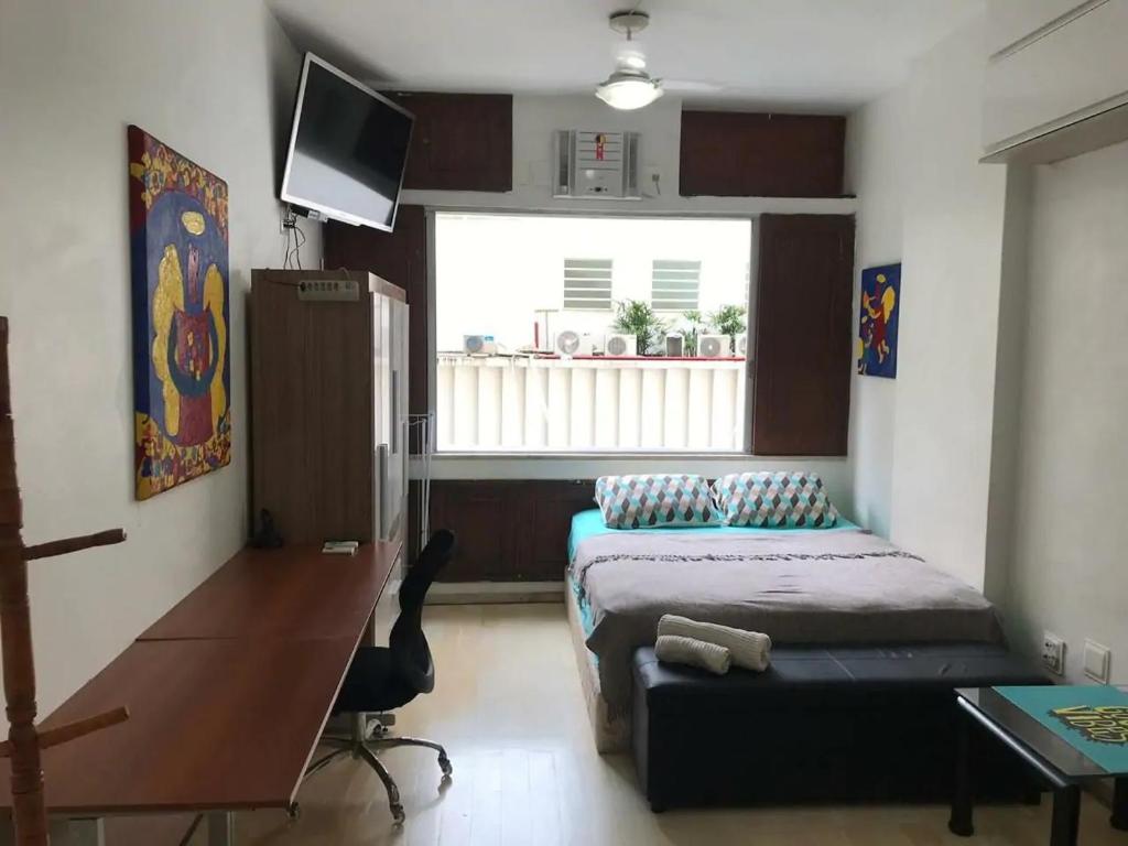 een slaapkamer met een bed, een bureau en een raam bij Ótimo Conjugado - Estúdio - Praia do Flamengo - RJ in Rio de Janeiro