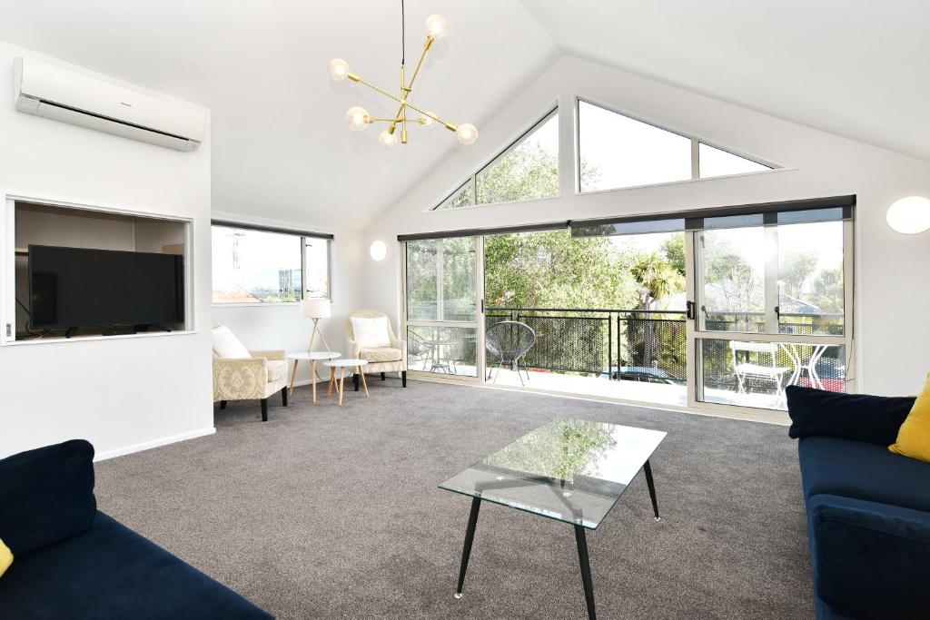 uma sala de estar com um sofá azul e uma televisão em Moa Place - Christchurch Holiday Homes em Christchurch