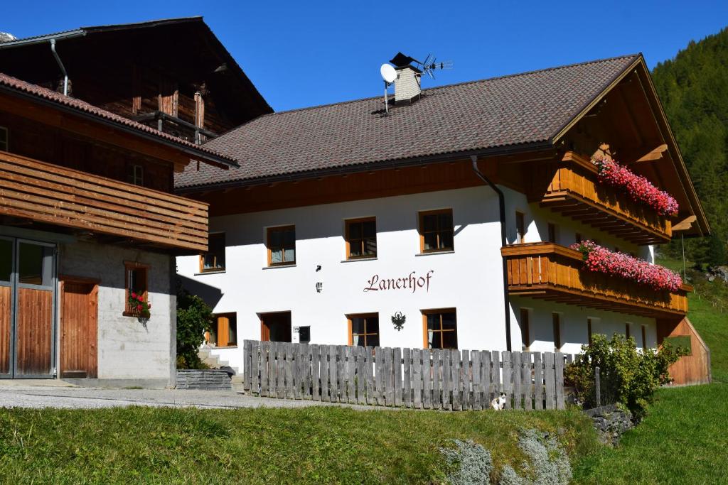 Ein weißes Gebäude mit einem Zaun davor. in der Unterkunft Lanerhof in Rein in Taufers