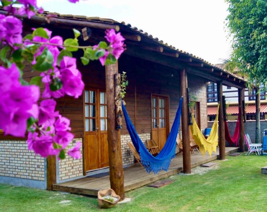 ein Haus mit Hängematten davor mit Blumen in der Unterkunft Mandala Chalés in Guarda do Embaú