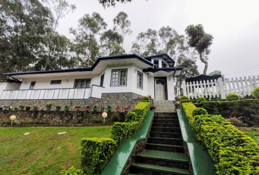 a white house with stairs in front of it at Windsor Forest bungalow in Bandarawela