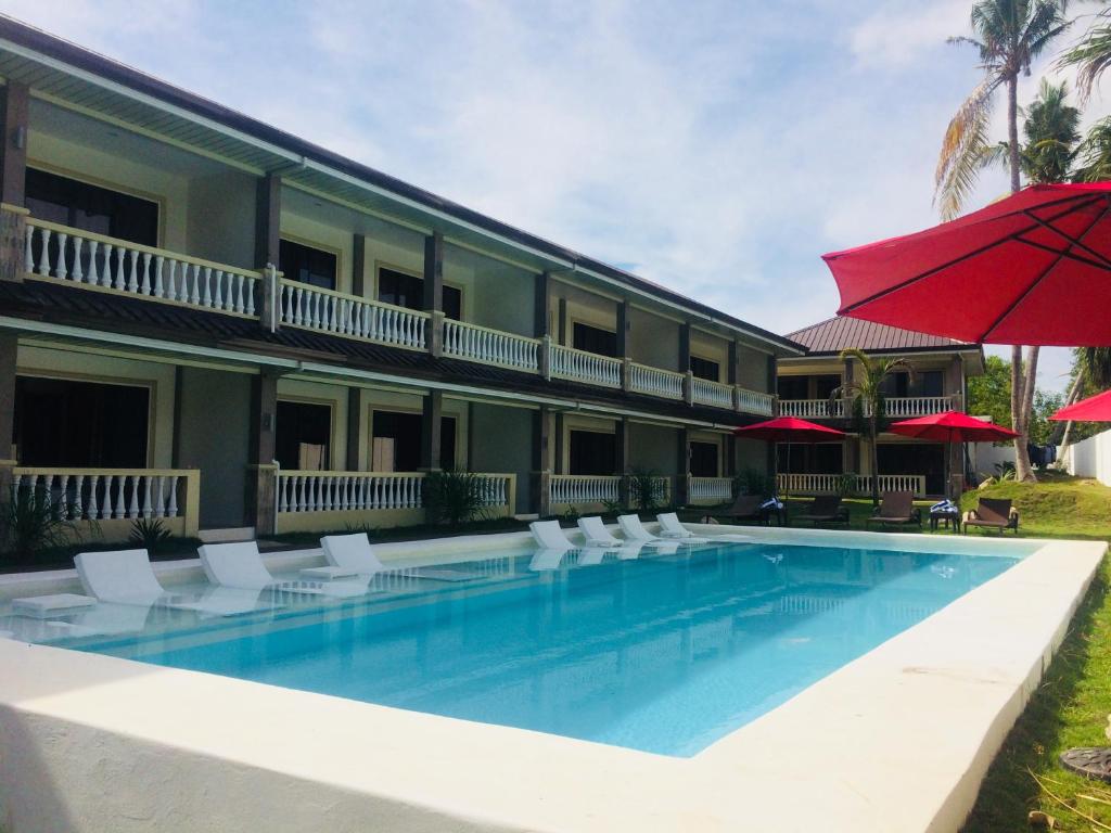 a hotel with a swimming pool with chairs and an umbrella at Portofino Panglao Bohol in Panglao