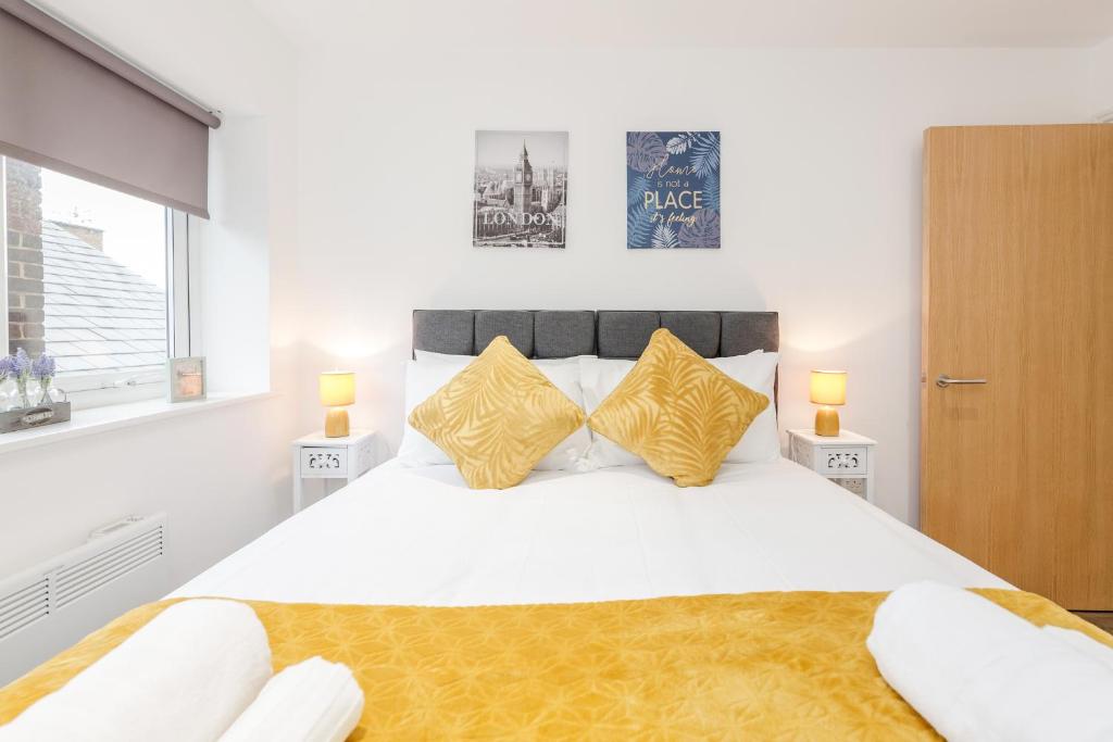 a bedroom with a large white bed with yellow pillows at Watford Town Centre, Serviced One Bed Flat with choice of King or Twin Beds, Sleeps Up To 4 Sharing, FREE WiFi and FREE Movies in Watford