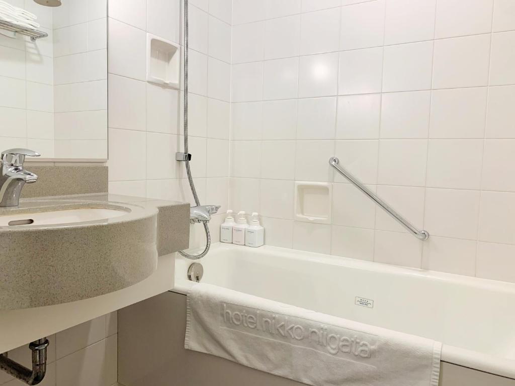 a bathroom with a tub and a sink and a towel at Hotel Nikko Niigata in Niigata