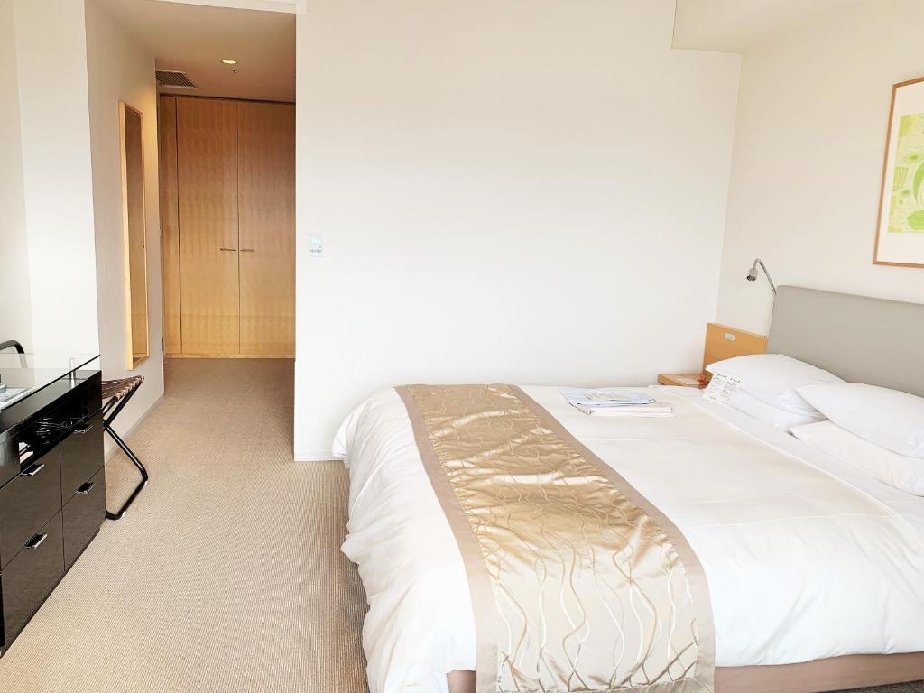 a hotel room with a bed and a dresser at Hotel Nikko Niigata in Niigata