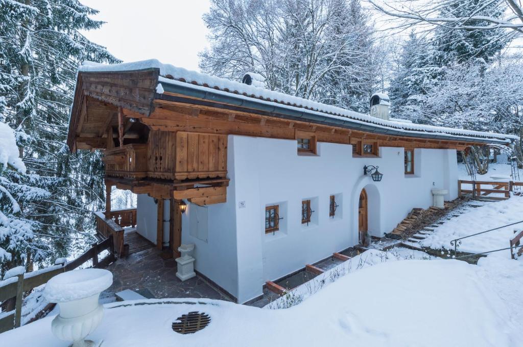 a house covered in snow in the woods at Das Kitz - deLuxe Chalet Valerie in Reith bei Kitzbühel
