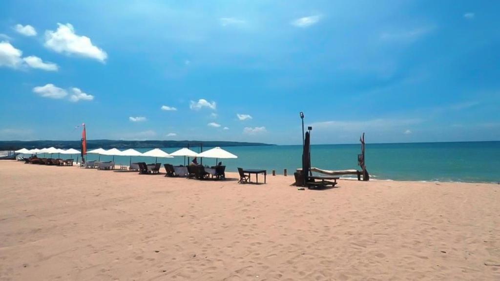 una playa con sillas y sombrillas y el océano en Villa Happy Jimbaran, en Jimbaran