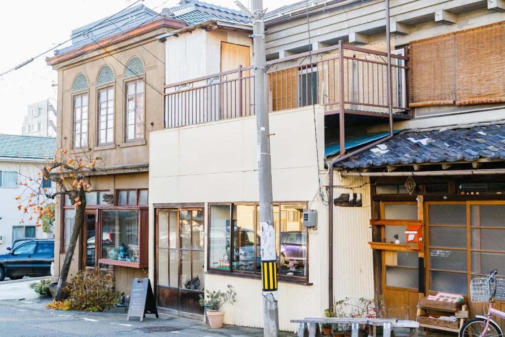 a white building with a balcony on a street at 1166 Backpackers in Nagano