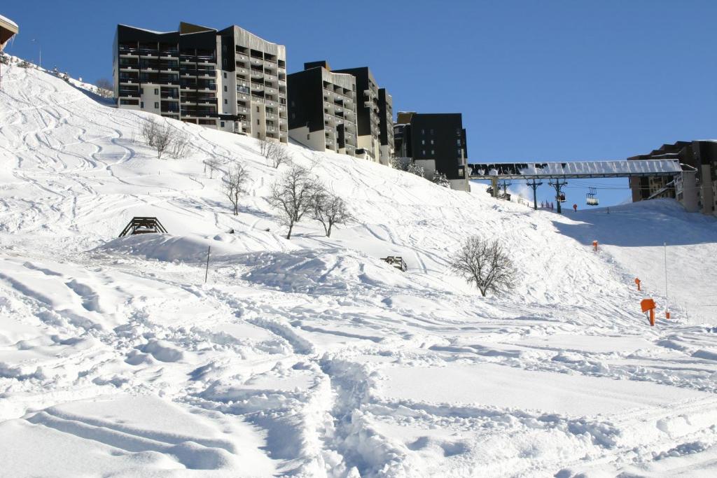 uma colina coberta de neve com edifícios ao fundo em Azureva Les Menuires em Les Menuires