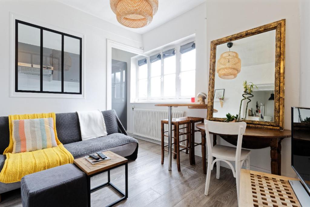 a living room with a couch and a table and a mirror at La Trouv in Trouville-sur-Mer