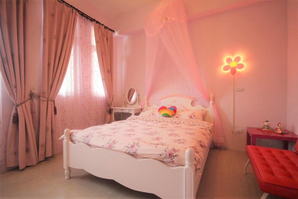 Dormitorio rosa con cama blanca con dosel en 萩閣民宿Sara's House走路可到夜市近市區好停車, en Hualien City