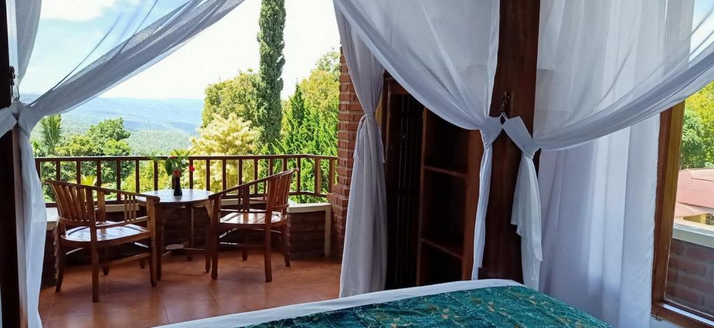 Schlafzimmer mit einem Bett und einem Tisch mit Stühlen auf dem Balkon in der Unterkunft KARANG SARI Guesthouse in Munduk