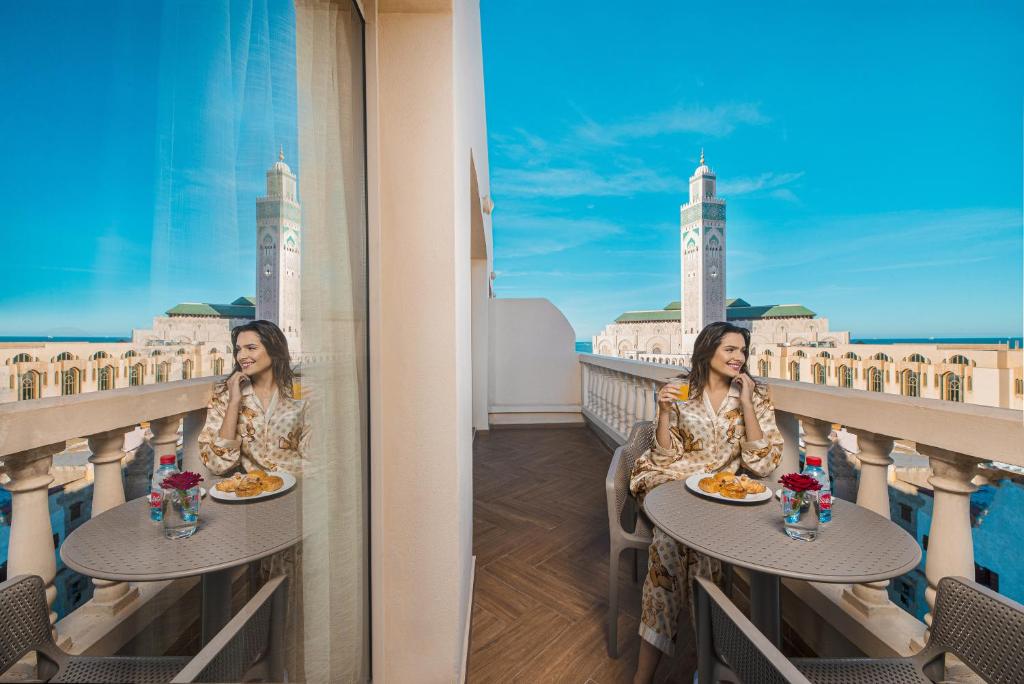 une femme assise à une table sur un balcon avec nourriture dans l'établissement Melliber Appart Hotel, à Casablanca