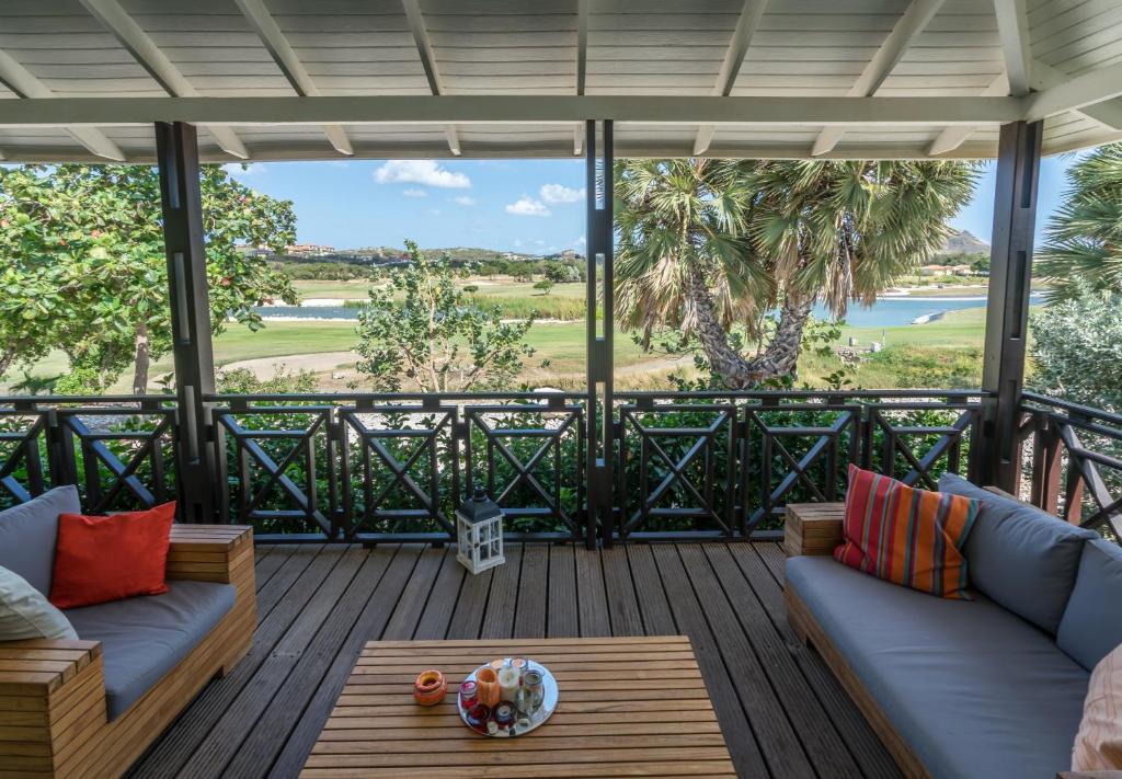 Blue Bay Beach Villa at Pool and Golfcourse في الخليج الأزرق: شاشة في الشرفة مع الأرائك وطاولة
