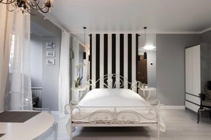 a white bed in a room with a striped wall at Charming studio in Pechersk in Kyiv