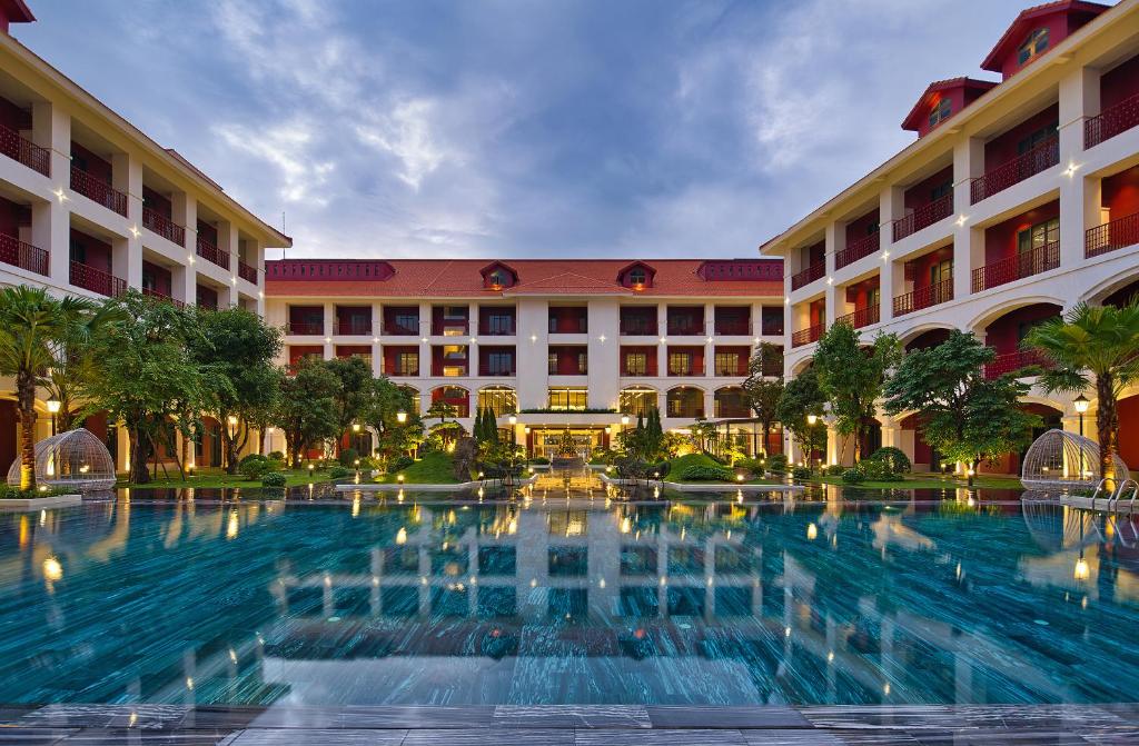 a hotel with a large swimming pool in front of a building at Senna Hue Hotel in Hue