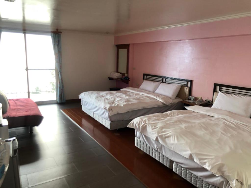 a bedroom with two beds and a pink wall at Cingjing Four Seasons B&amp;B in Ren&#39;ai